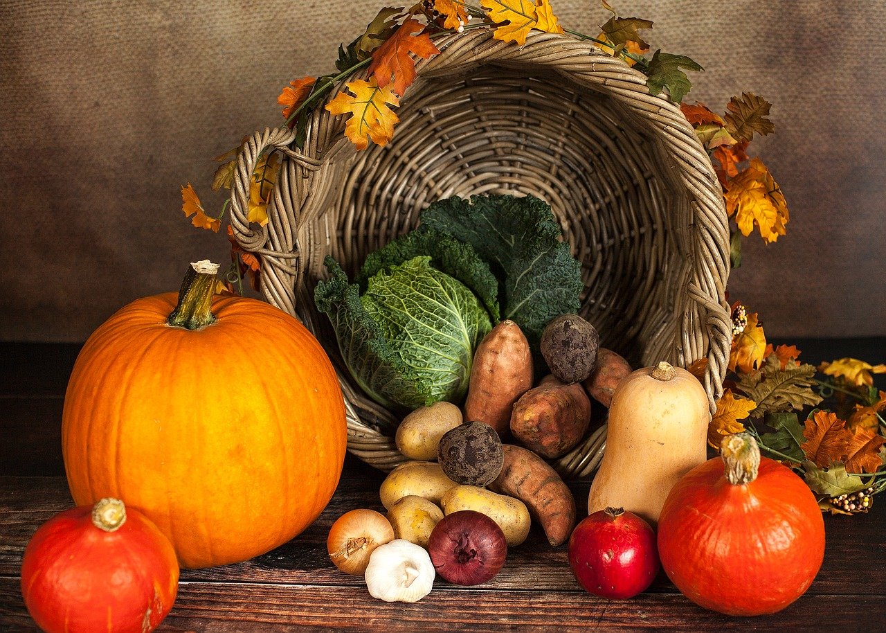 a basket with autumn vegetables like pumpkin, cabbage, and potatoes