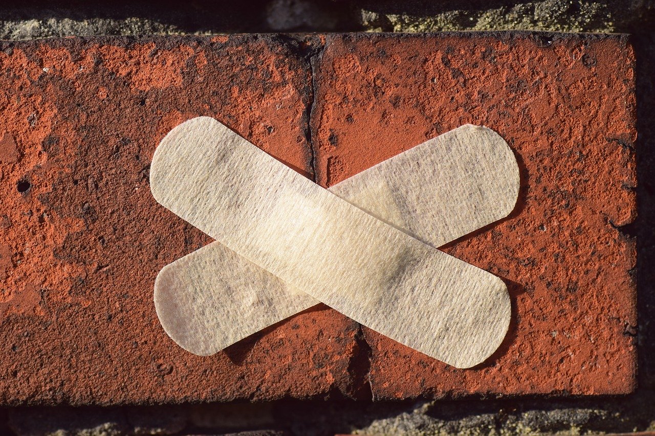 crossed bandaid covering a cracked brick