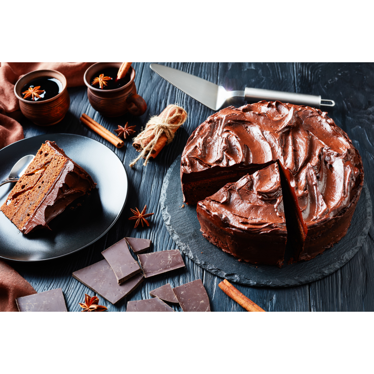 Professional chocolate cake with pieces of chocolate bars, spices, and a slice of cake on black plates and a black table.