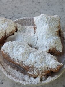 Close-up image of three fresh beignets from Cafe De Monde on a white table.