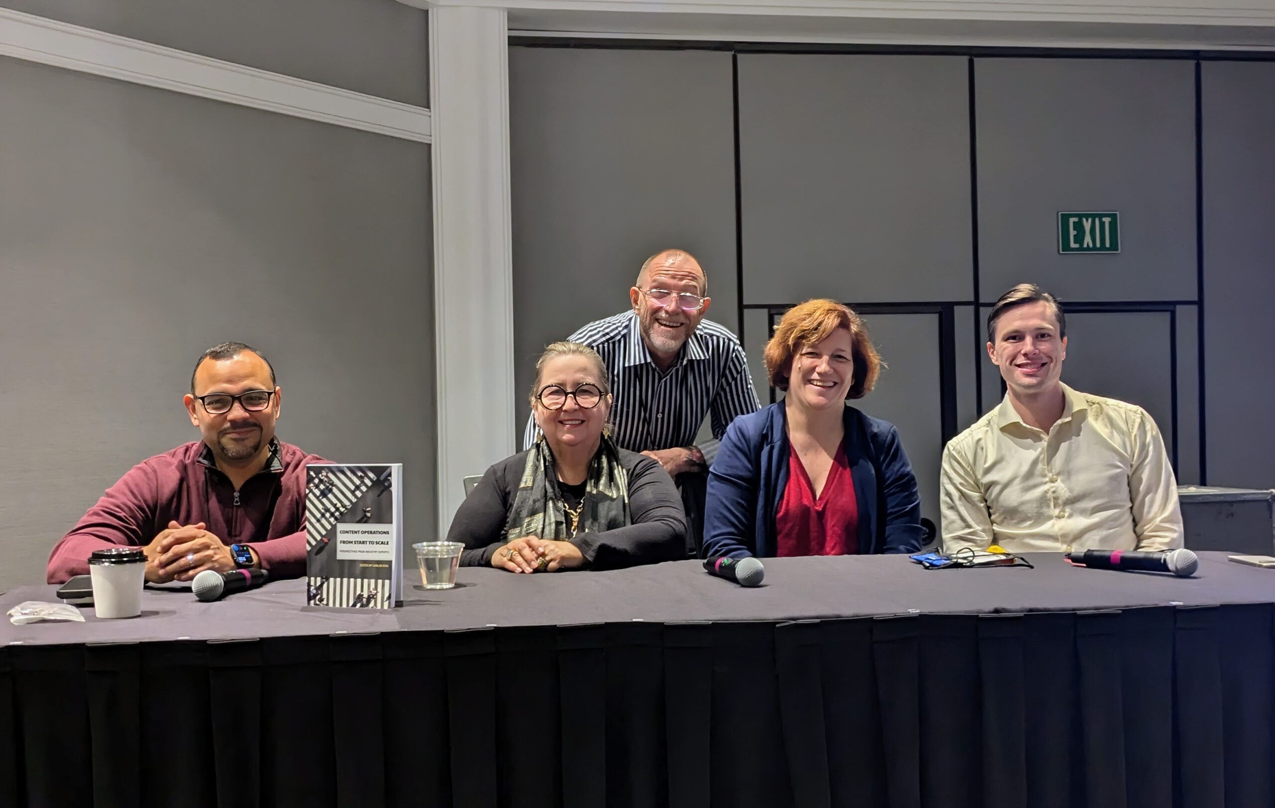 Five panelists sit at a long table, smiling for the camera. A book titled "Content Operations: From Strategy to Scale" is displayed in front of the panel. The group includes three men and two women, all casually dressed, seated with microphones ready for discussion.