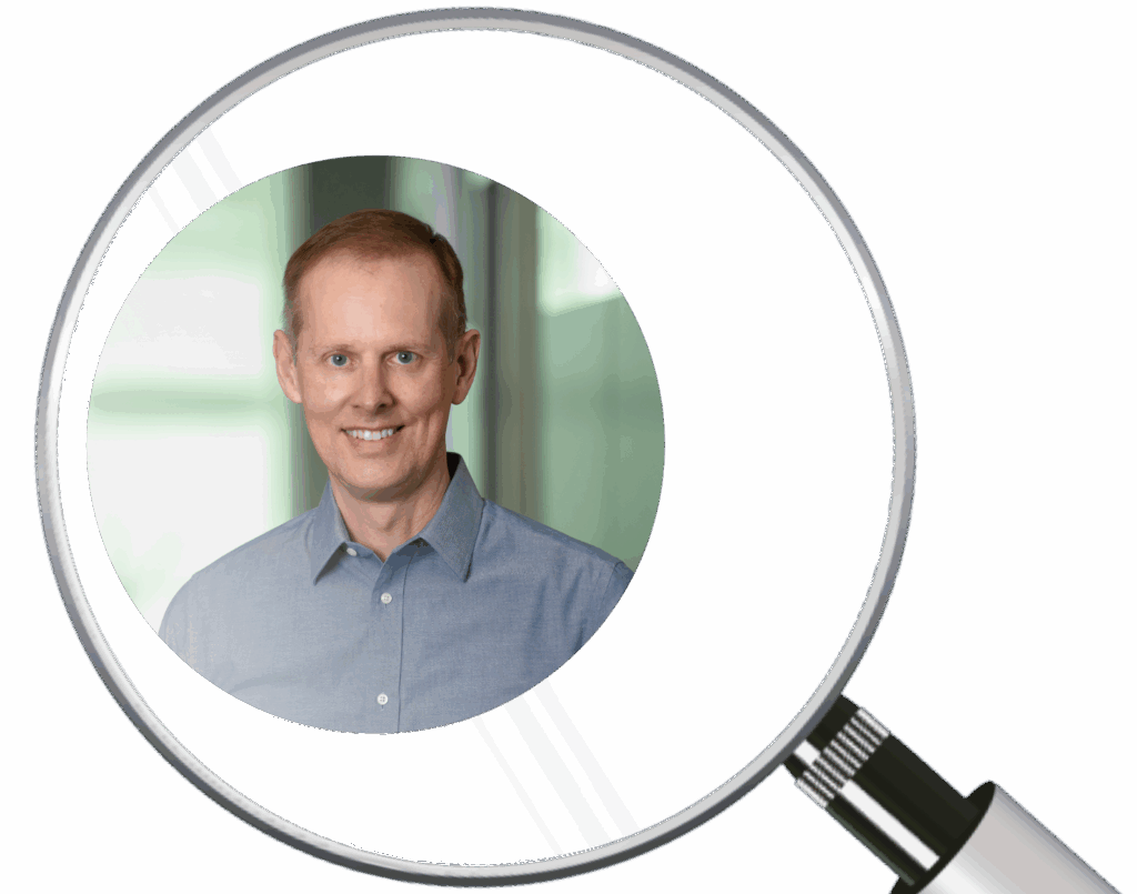 Magnifying glass hovering over a picture of a man in business attire.